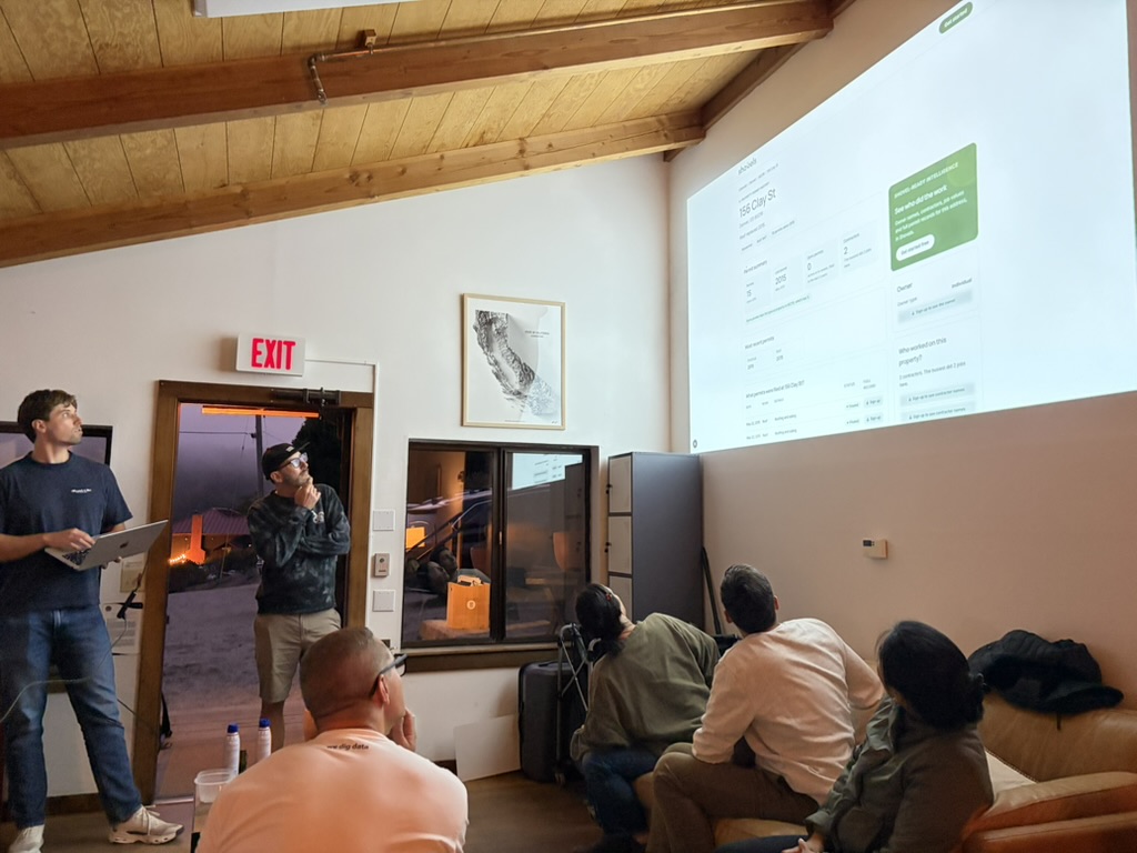 A Shovels team member presents a property-history prototype to colleagues at the Point Reyes hackathon, the Shovels Online address page projected on the wall.